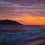 sea waves crashing on shore during sunset